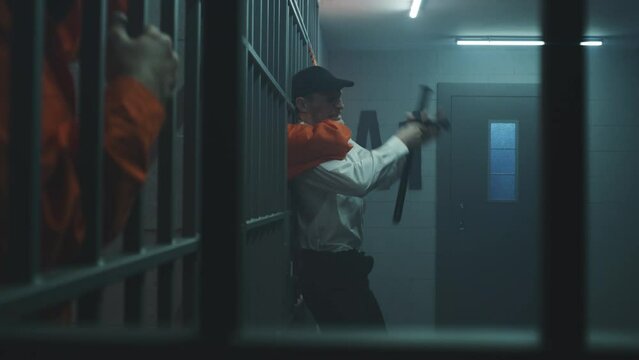 Male prisoner strangles prison officer through metal bars, takes keys and opens prison cell. Criminal in orange uniform escapes from jail. Serving term in detention center or correctional facility.