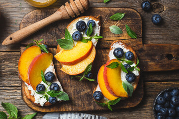 White bread sandwich with peaches, blueberries on a wooden board