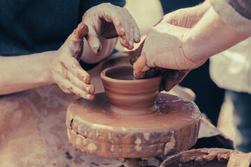 hands of a potter, creating an earthen jar on a pottery wheel