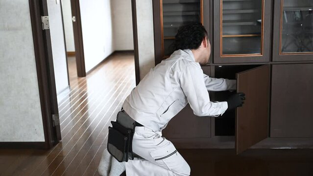 戸棚の扉の修理や蝶番などを点検する作業員の動画