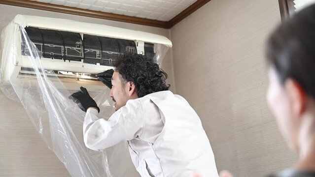  Slow motion picture of a worker cleaning and inspecting an air conditioner (cooling or heating) No face