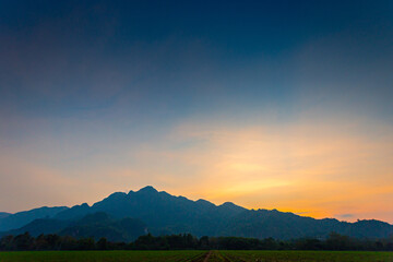 Paddy rice field with sunset sky and Doi Nang Non Mountains background in Chiangrai Thailand