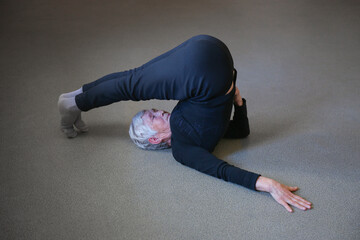 An elderly woman does gymnastics. The age of the woman is 75 years old.