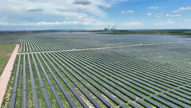 Solar farm aerial establishing shot. Rising drone shot of massive solar energy plant in USA. Rows of photovoltaic cells and inverters.