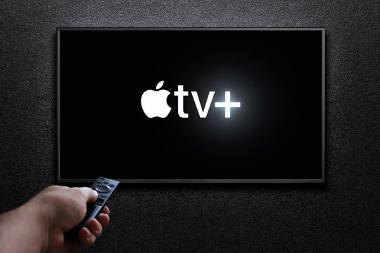 Apple TV plus logo on TV screen. Man turns on TV with remote control. Apple TV plus is an American subscription streaming service. Astana, Kazakhstan - July 21, 2023.
