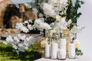 Candles. Decor details closeup. Location for luxury wedding ceremony. Arch decorated white flowers,...