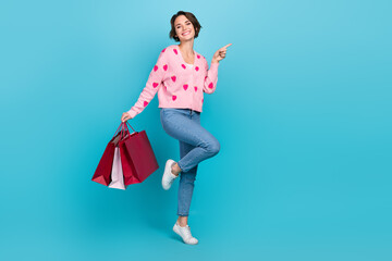 Full body cadre of funky young woman strawberry jumper directing her finger novelty packages bargains isolated on blue color background
