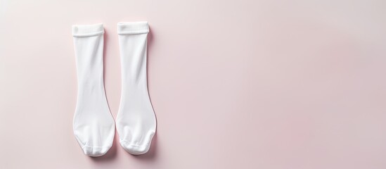 Photo of a pair of white socks on a pink surface with blank space for text or design with copy space