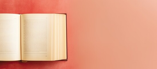 Photo of an open book resting on a vibrant red wall, creating a visually striking contrast with copy space