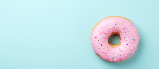 Photo of a delicious pink frosted donut with colorful sprinkles on a vibrant blue background with copy space