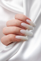 A woman's hands with a manicure on them, the nails are painted in a white color.