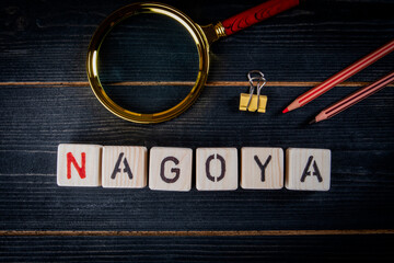 NAGOYA. City name from alphabet letters on dark wood texture background