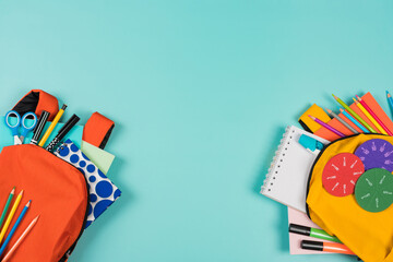 Back to school, education, learning concept. Two open backpacks with school supplies on pastel blue background. Top view