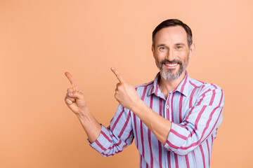 Portrait of satisfied toothy beaming person with beard striped shirt directing at promo empty space isolated on pastel color background