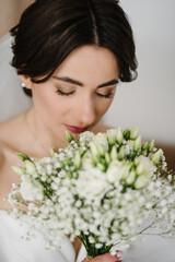 Young fashion model with perfect skin and professional makeup. A bride in a stylish dress at home. Luxury wedding day. Fashion photo. Waiting for the groom. Trendy wedding style shot. Closeup.