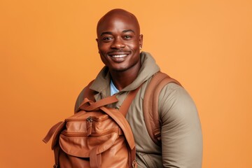 Portrait of smiling african american man with backpack against orange background - Powered by Adobe