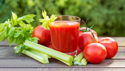 fresh tomato juice in glass with celery sticks and heap of ripe vegetables on wooden table outdoors