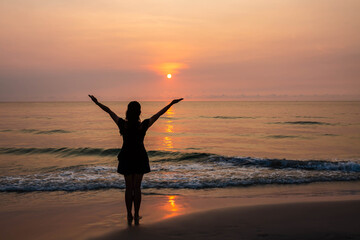 Fototapeta na wymiar Silhouettes of Woman raise hands up to the sunset sky praise and worship God against the sun at the beach with copy space for your text, Christian praise and worship concept 