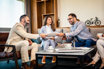 Teamwork. Team discussing something and smiling while sitting at the modern business lounge.
