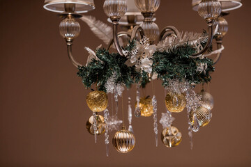 Stylish gold and crystal-clear toys on the Christmas tree. Beige tones. The concept of interior decoration and stylish new year and Christmas 2024.