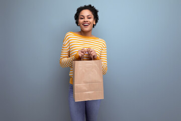 afro brunette latin young woman holding craft gift bag