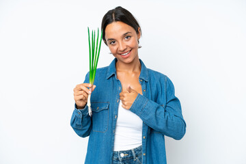 Young hispanic woman holding chive isolated on white background giving a thumbs up gesture