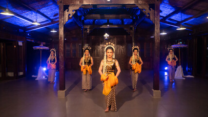a group of Javanese dancers with their faces full of makeup and jasmine on their heads dance
