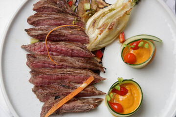 Delicious cuts of medium rare beef tenderloin with with herbed steak sauce served on the restaurant table