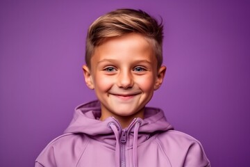 Portrait of a smiling little boy in a purple hoodie on a purple background