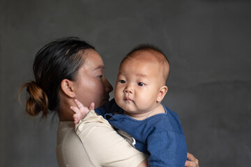 Mom hugging infant baby boy with blur background