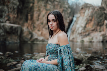 Modelo joven con vestido azul posa en un lago