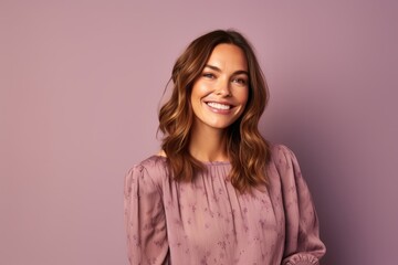 Portrait of a happy young woman smiling at the camera while standing against purple background