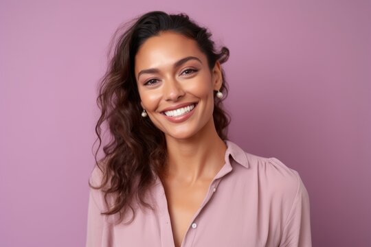 Portrait of a beautiful young woman smiling at the camera on a purple background