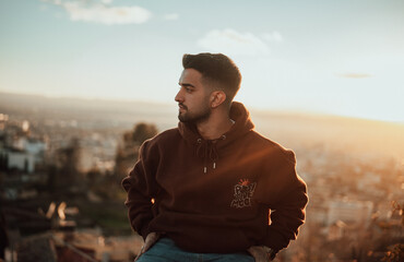 Chico joven posa con puesta de sol de fondo