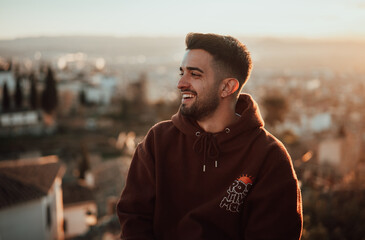 Chico joven posa con puesta de sol de fondo