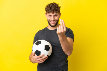 Handsome young football player man isolated on yellow background making money gesture