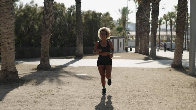 African woman running along a public park