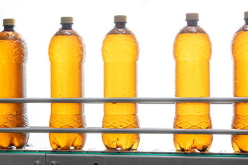 Brown plastic bottles with beer moving on conveyor, white isolated background. Concept production line of brewery