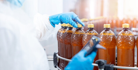Concept brewery food industry banner. Factory worker with computer tablet inspecting production line with brown plastic bottles with beer