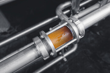 Brewing equipment for quality control, sight glass full of golden beer on stainless steel pipe....