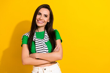 Photo of pretty confident girl dressed green t-shirt arms crossed looking empty space isolated yellow color background