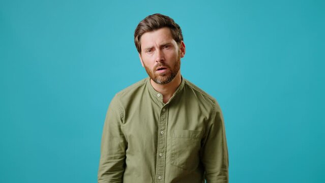 Worried bearded man stares and makes facepalm gesture