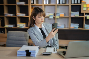 businesswoman sits in a office working on smartphone play social media and enjoys a coffee.