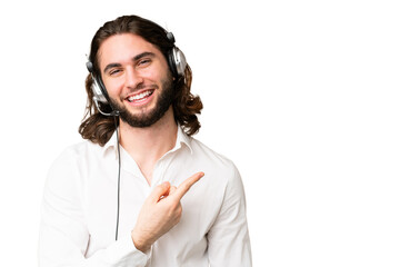 Telemarketer man working with a headset over isolated chroma key background pointing to the side to...