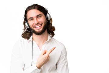 Telemarketer man working with a headset over isolated chroma key background pointing to the side to present a product