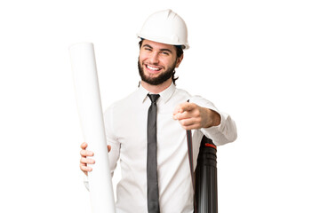 Young architect man with helmet and holding blueprints over isolated chroma key background pointing front with happy expression