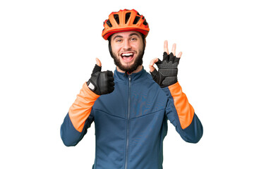 Young cyclist man over isolated chroma key background showing ok sign and thumb up gesture - obrazy, fototapety, plakaty