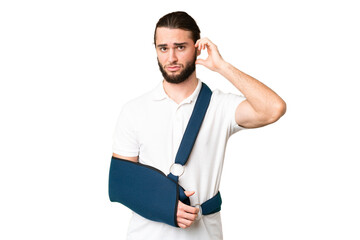 Young handsome man with broken arm and wearing a sling over isolated chroma key background having...