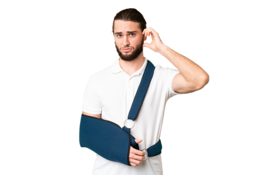 Young handsome man with broken arm and wearing a sling over isolated chroma key background having doubts