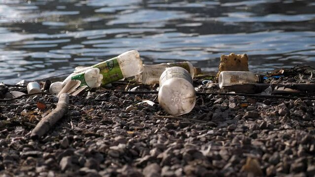 Close-up of plastic garbage, bottles and bags, on the riverbank. Discarded bottle plastic garbage river waste. Ecology pollution of nature. Environmental problems river pollution garbage water trash. 